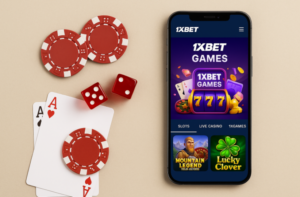 هاتف ذكي يعرض واجهة ألعاب الكازينو في تطبيق 1xBet، موضوع بجانبه رقائق كازينو حمراء، نرد أحمر، وأوراق لعب (آص قلب وآص بستوني)، على خلفية بلون بيج. تظهر على شاشة الهاتف رموز ألعاب سلوت وكازينو مباشر ضمن تصميم جذاب.